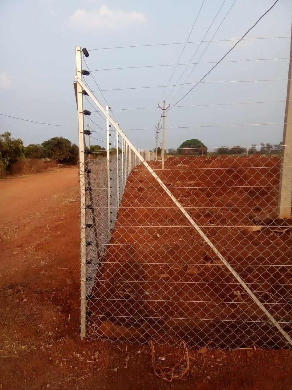 White solar fencing posts and chain link fence on red soil land
