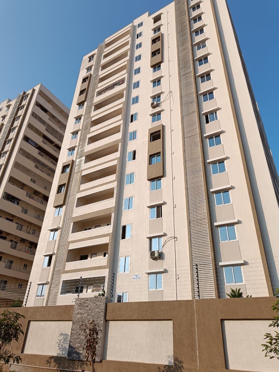 Tall apartment tower with solar fencing on compound wall